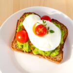 Avocado toast on whole grain bread with cherry tomatoes and a poached egg on top